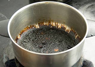 Steel cooking pan charred by burnt sugar